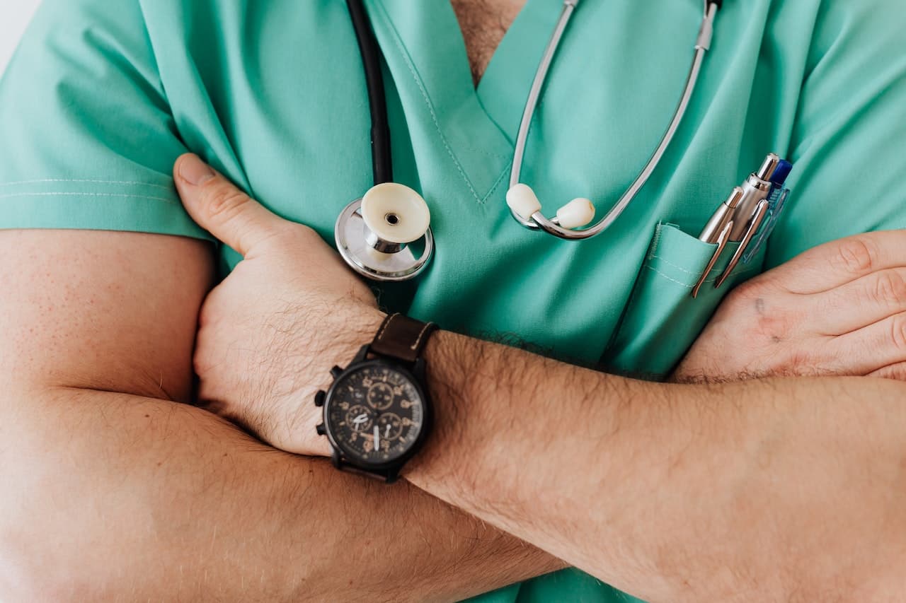 close-up of arms folded, man in scrubs with stethoscope