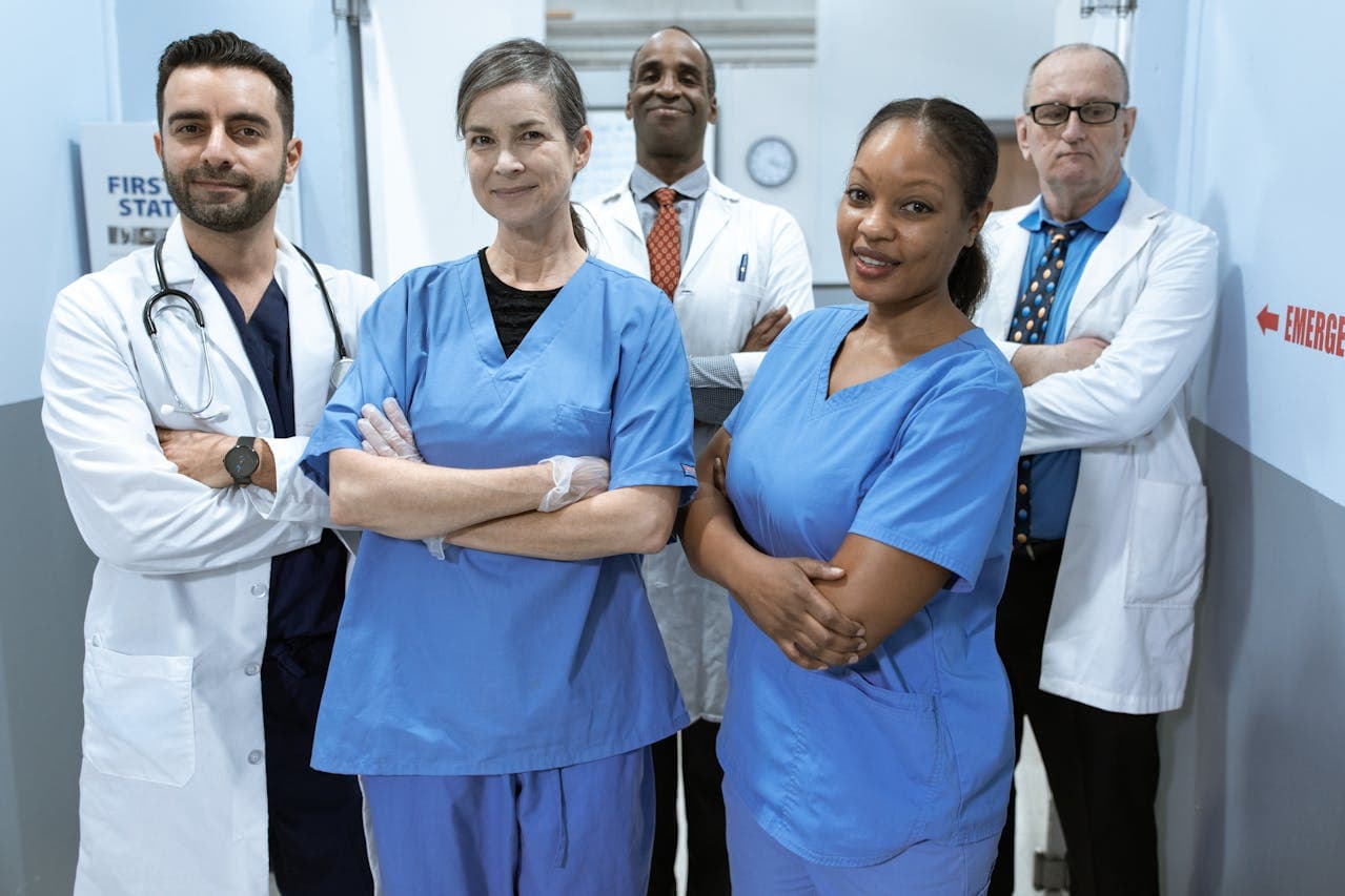 A group of people in scrubs and doctor white coats smiling into the camera