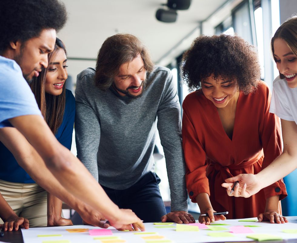 Group of diverse people looking at post-it notes on a table