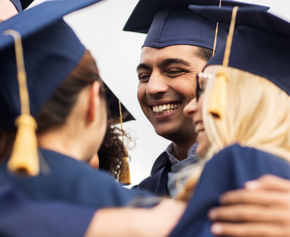 A group of graduates smile and embrace