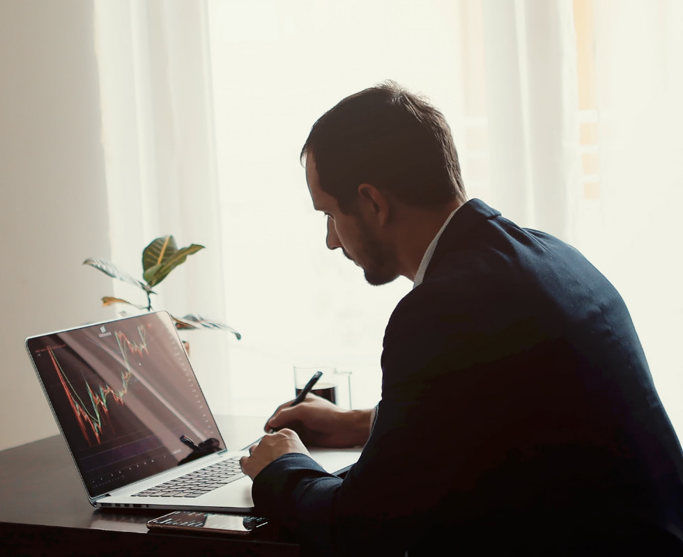 A man in a suit works at his desk on the computer