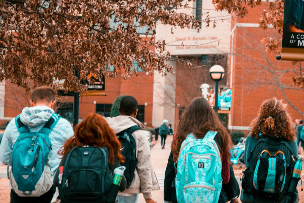 young adults walking towards a building with backpacks on